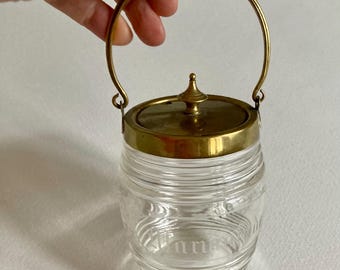 Tarro de mermelada antiguo de cristal grabado y latón, con asa.