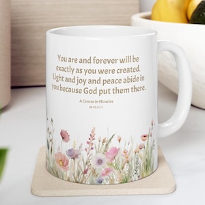 May include: White ceramic mug with a floral design and the text "You are and forever will be exactly as you were created. Light and joy and peace abide in you because God put them there. A Course in Miracles W-93.7:1-7"