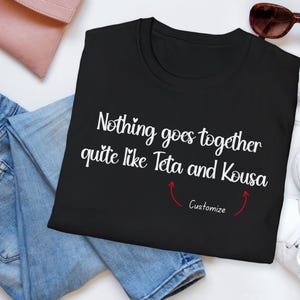 May include: Black t-shirt with the white text "Nothing goes together quite like Teta and Kousa." Red arrows point to the word "Customize" below the text. The shirt is next to blue jeans, a pink clutch, sunglasses, and white sneakers.