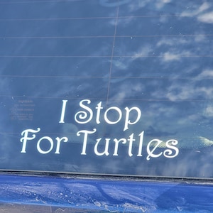 May include: A white vinyl sticker on a blue car window that reads "I Stop For Turtles".