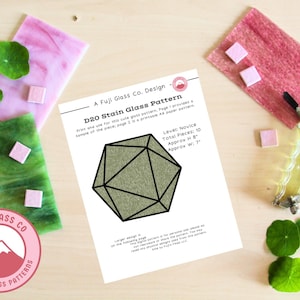 Könnte beinhalten: Ein druckbares Bleiglasmuster für einen D20, einen zwanzigseitigen Würfel. Das Muster ist für Anfänger geeignet und umfasst 10 Teile. Das fertige Projekt wird etwa 20 cm hoch und 18 cm breit sein.