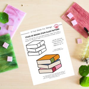 Op de afbeelding: Een ontwerp voor een glas-in-loodpatroon getiteld "Stack of Books" door A Fuji Glass Co. Het ontwerp toont een stapel boeken, met afmetingen van ongeveer 13 cm hoog en 18 cm breed. De afbeelding toont ook roze en groene glasstalen.