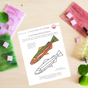 Puede incluir: Un patrón de vitral imprimible para un pez trucha. El patrón es para un artesano principiante e incluye 15 piezas de vidrio, con un ancho aproximado de 7,6 cm y una altura de 7,6 cm. El patrón está sobre un fondo blanco con líneas negras.