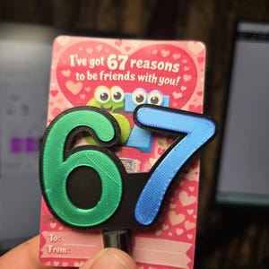 May include: A friendship card with the text "I've got 67 reasons to be friends with you!" and a 3D-printed "67" in green and blue. The card has a pink background with white hearts and space to write "To:" and "From:"