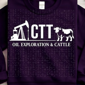 May include: A dark purple sweatshirt with a white graphic. The graphic includes an oil derrick, the letters "CTT", and a cow, with the words "OIL EXPLORATION & CATTLE" below. The sweatshirt has a crew neck and long sleeves.