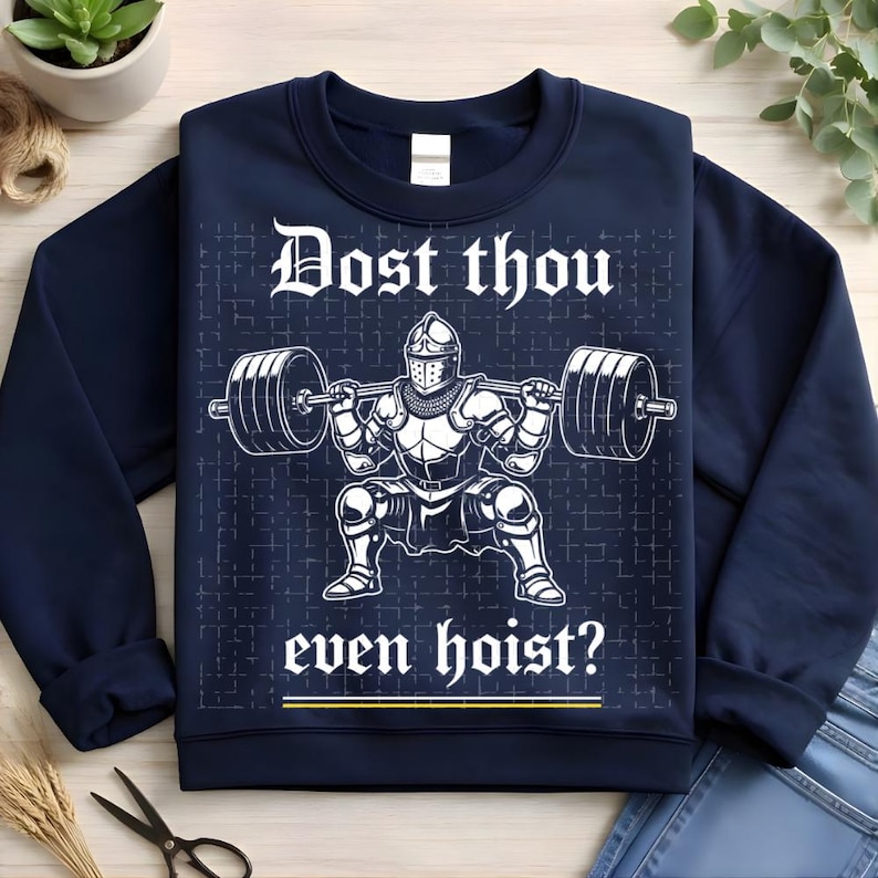 K&ouml;nnte beinhalten: Marineblaues Sweatshirt mit wei&szlig;er Grafik eines Ritters, der Gewichte hebt, mit dem Text "Dost thou even hoist?" in einer mittelalterlichen Schriftart. Das Design hat einen gitterartigen Hintergrund. Eine humorvolle Interpretation von Fitness und mittelalterlichen Themen.