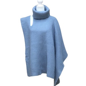 May include: A light blue turtleneck sweater with a cut-out detail on the shoulder. The sweater is made of a soft, ribbed knit fabric.