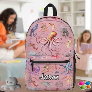 May include: Pink backpack with a repeating pattern of colourful octopus illustrations. The backpack has a black zip, a black handle, and the name "Jason" printed on the front.