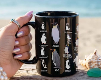 May include: A black ceramic mug featuring a graphic print of various penguin species, including Emperor, King, African, and Galapagos, each labelled with its name in white text. The mug has a smooth, glossy finish and a curved handle on the left side.