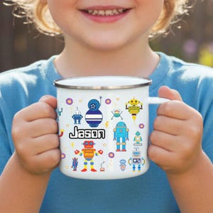 May include: A white enamel mug with two handles featuring a colorful pattern of various small robots and the name Jason printed in black text. The mug has a silver-colored metal rim and a smooth finish, designed for holding beverages with ease.