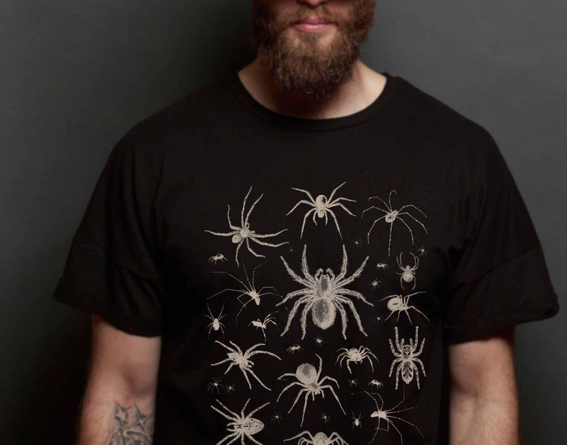 May include: A person wearing a black t-shirt with a white print of various spiders and insects.