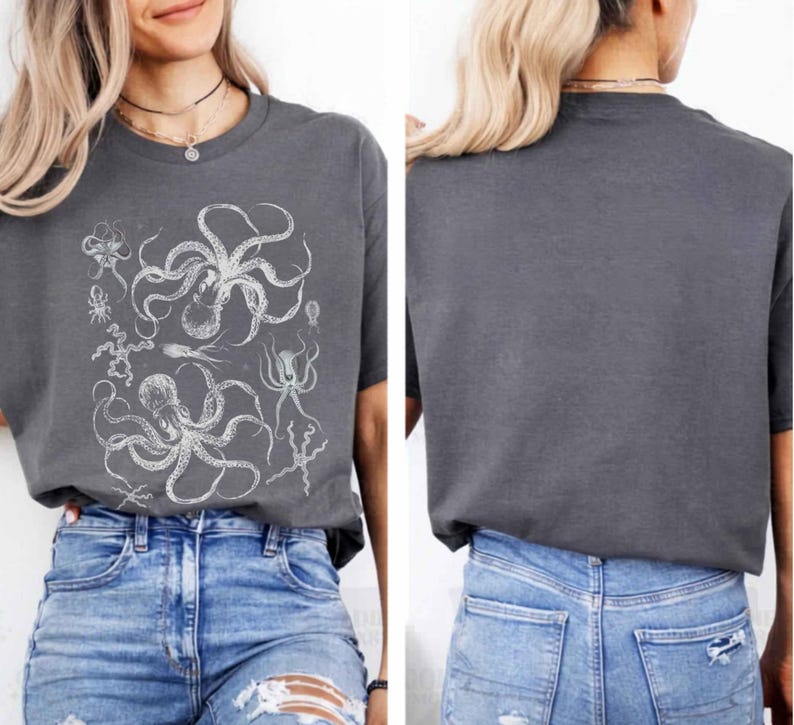 May include: A charcoal gray short-sleeve t-shirt featuring a white graphic print of multiple octopuses and sea creatures on the front. The back of the t-shirt is plain charcoal gray. The shirt is paired with blue denim jeans with distressed details.