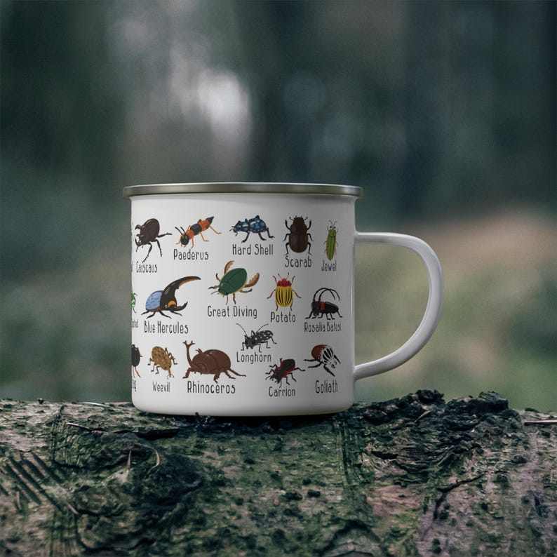 K&ouml;nnte beinhalten: Wei&szlig;er Emaillebecher mit farbigen Insektenillustrationen, darunter K&auml;fer und Skarab&auml;en, mit ihren Namen. Der Becher hat einen silbernen Rand und einen wei&szlig;en Henkel. Der Becher steht auf einem Baumstamm.