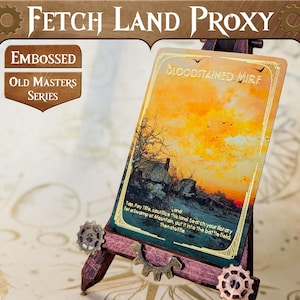 May include: A Bloodstained Mire Magic: The Gathering card proxy with a gold foil finish. The card features a sunset landscape with a dark silhouette of a building in the foreground. The card text reads "Tap, Pay 1 life, sacrifice this land: Search your library for a Swamp or Mountain, put it onto the battlefield, then shuffle."
