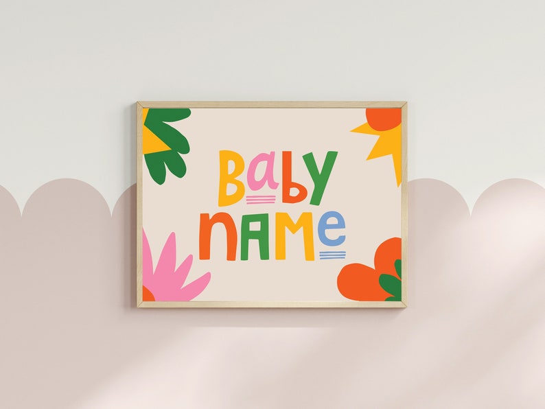 Puede incluir: Un estampado enmarcado con las palabras "BABY NAME" en letras coloridas y juguetonas. El dise&ntilde;o incluye formas florales y abstractas brillantes en naranja, rosa, verde y amarillo sobre un fondo crema. El marco es de color madera clara.