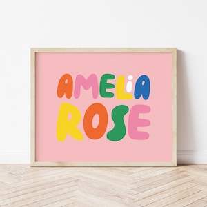 Puede incluir: Una impresión enmarcada rosa con el nombre "Amelia Rose" en letras coloridas y redondas.