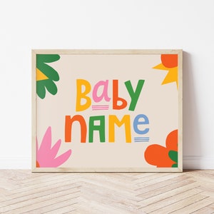 Puede incluir: Un estampado enmarcado con las palabras "BABY NAME" en letras coloridas y divertidas. El dise&ntilde;o incluye formas florales y abstractas en tonos verdes, naranjas, rosas y amarillos sobre un fondo beige. El marco es de color madera clara.