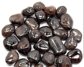May include: A collection of tumbled black and brown garnet stones. The stones are smooth and polished, with a variety of shapes and sizes.