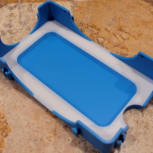 以下が含まれることがあります： 白い裏地が付いた青いプラスチック製の携帯電話ケース。ケースは携帯電話を安全に保持するように設計されています。
