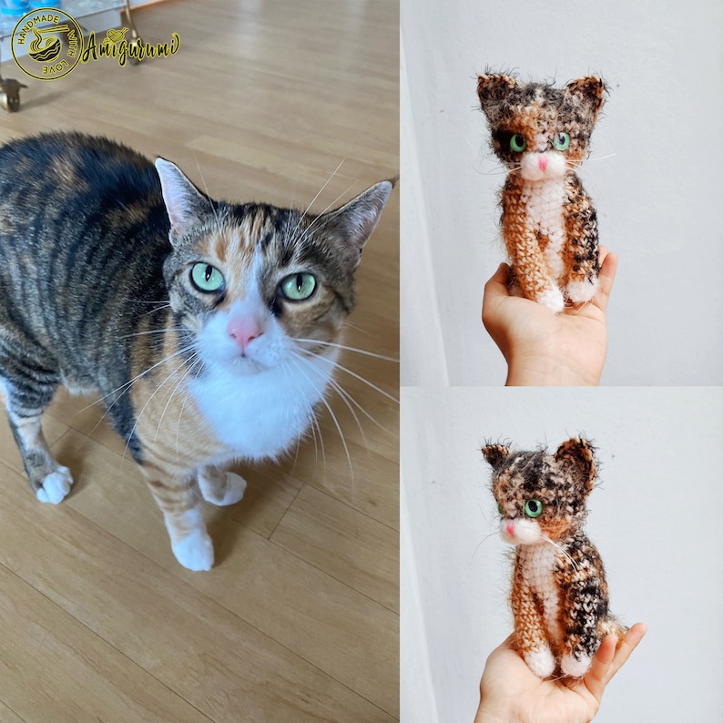 May include: A calico cat with green eyes and a white chest is standing on a wooden floor. Next to the cat is a crocheted calico cat with green eyes and a white chest. The crocheted cat is being held in a hand. The image includes the text "Handmade with Love Amigurumi".