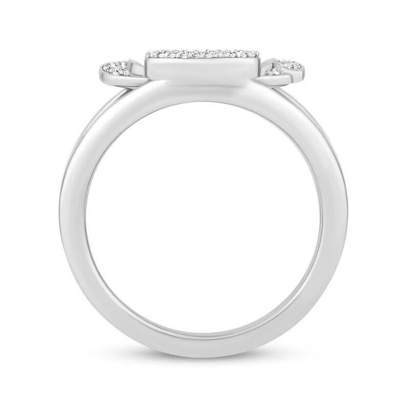 Puede incluir: Un anillo de plata con una piedra central de forma cuadrada y dos piedras m&aacute;s peque&ntilde;as a cada lado. El anillo est&aacute; engastado con peque&ntilde;os diamantes.