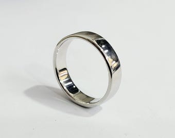 May include: A polished, silver ring with a flat top and rounded edges. The ring reflects light, creating highlights and shadows. The band is approximately 4mm wide. The ring is set against a white background.