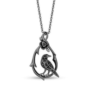 May include: A black silver-tone necklace with a pendant featuring a black crow perched on a thorny branch with a black rose.