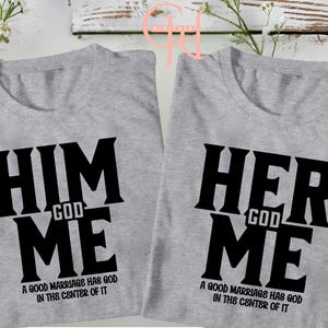 Puede incluir: Dos camisetas grises con texto negro. Una camiseta dice "HIM GOD ME" y la otra dice "HER GOD ME". Debajo del texto de ambas camisetas está la frase "A GOOD MARRIAGE HAS GOD IN THE CENTER OF IT."