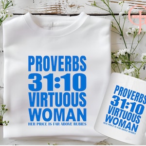 Op de afbeelding: Wit T-shirt en mok met blauwe tekst. De tekst op beide luidt "SPREEUWEN 31:10 DEUGDZAME VROUW HAAR PRIJS IS VER BOVEN ROBIJNEN." Het shirt is opgevouwen en de mok ligt op zijn kant. Witte bloemen staan op de achtergrond.