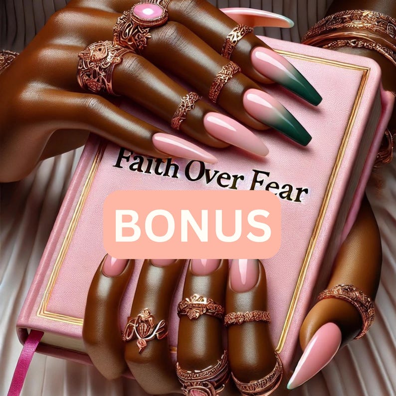May include: A pink book with the words "Faith Over Fear" and "BONUS" is held by a hand with long, pink and green ombre nails. The hand is adorned with multiple gold rings. A pink ribbon marks a page.
