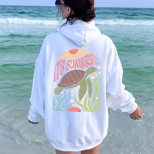 May include: White hooded sweatshirt with a graphic of a sea turtle swimming in the ocean with the text "It's Summer!" printed on the back.