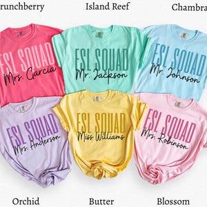 May include: Six short-sleeved t-shirts in various colors: pink, mint green, light blue, lavender, yellow, and light pink. Each shirt displays the text "ESL SQUAD" with a teacher's name below. The shirts are labeled with their color names.