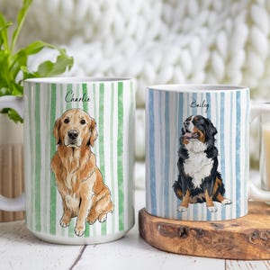 Może przedstawiać: Dwa białe ceramiczne kubki z ilustracjami psów. Jeden kubek przedstawia złotego retrievera o imieniu "Charlie" na zielonym tle w paski. Drugi kubek ma berneńskiego psa pasterskiego o imieniu "Bailey" na niebieskim tle w paski.