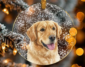 May include: A clear, round Christmas ornament featuring a golden retriever dog with the name "Akira" in white script. The ornament has a gold ribbon for hanging and is decorated with snowflakes.