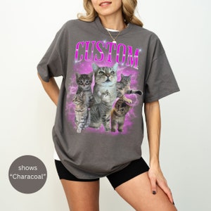 Pode incluir: Uma camiseta cinza-chumbo com uma estampa gr&aacute;fica de cinco gatos tigrados em um design de gal&aacute;xia rosa e roxo. O texto "CUSTOM" &eacute; impresso em rosa acima dos gatos.