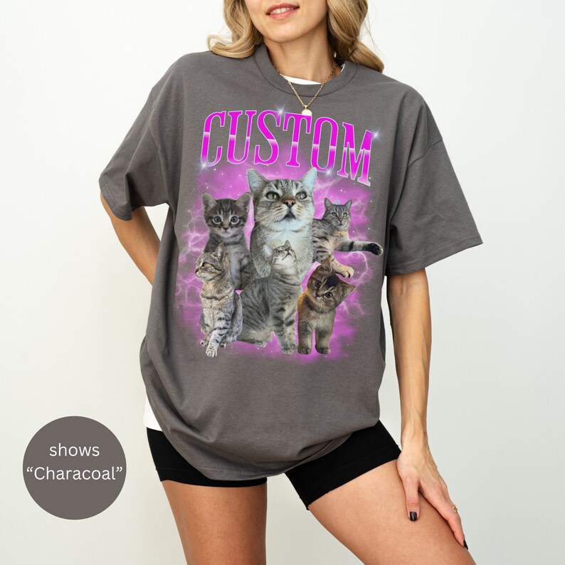 Pode incluir: Uma camiseta cinza-chumbo com uma estampa gr&aacute;fica de cinco gatos tigrados em um design de gal&aacute;xia rosa e roxo. O texto "CUSTOM" &eacute; impresso em rosa acima dos gatos.
