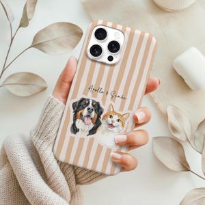 Op de afbeelding: Telefoonhoesje met beige en witte strepen. Het heeft een aquarel illustratie van een hond en een kat, met de namen "Apollo & Simba" erboven gedrukt. De hoes wordt in een hand gehouden.