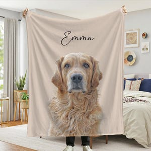 Könnte beinhalten: Eine beige Decke mit einem Porträt eines Golden Retriever-Hundes und dem Namen "Emma" in Schreibschrift. Der Hund hat hellbraunes Fell und ist auf der Decke zentriert. Die Decke wird in einem Schlafzimmer gehalten.