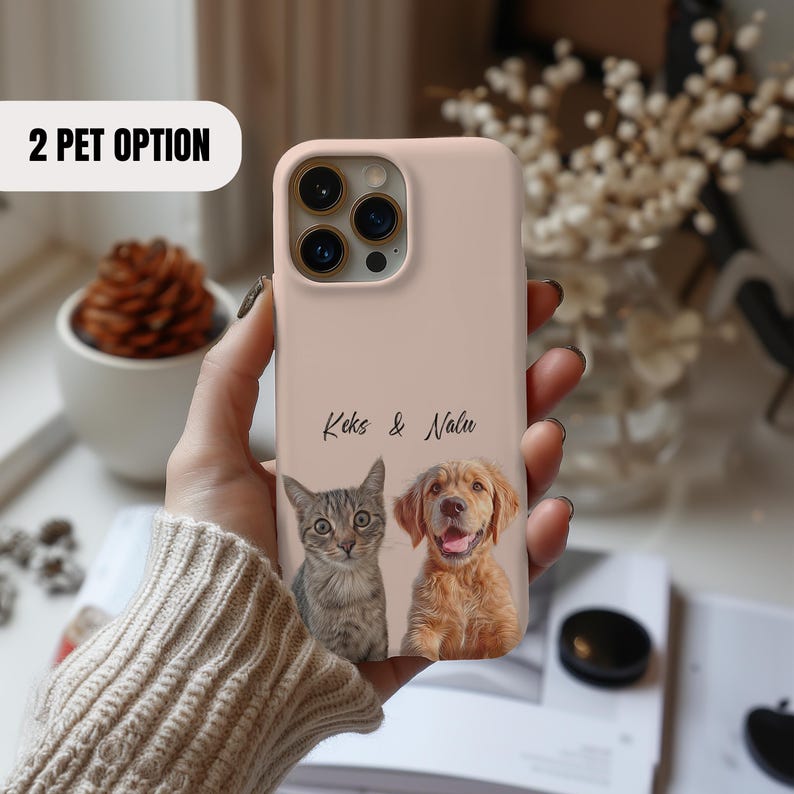 Pu&ograve; includere: Una custodia per telefono rosa con un gatto e un cane. Il testo "Keks & Nalu" &egrave; stampato sulla custodia.