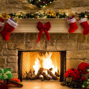 Pode incluir: Uma lareira com uma lareira crepitante, decorada com meias de Natal, uma guirlanda e uma árvore de Natal. A lareira é cercada por uma parede de pedra e há presentes embrulhados em papel colorido no chão.