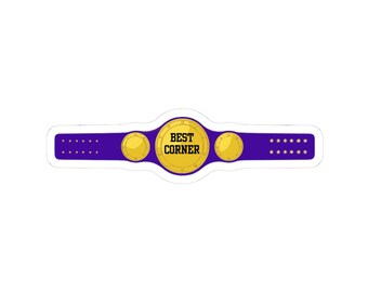 May include: A sticker featuring a championship belt design. The belt has a purple strap with gold accents and three gold medallions. The central medallion displays the text "BEST CORNER" in black.