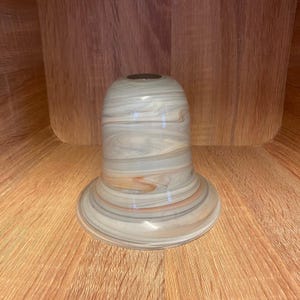 May include: A white and brown glass lampshade with a swirl pattern.