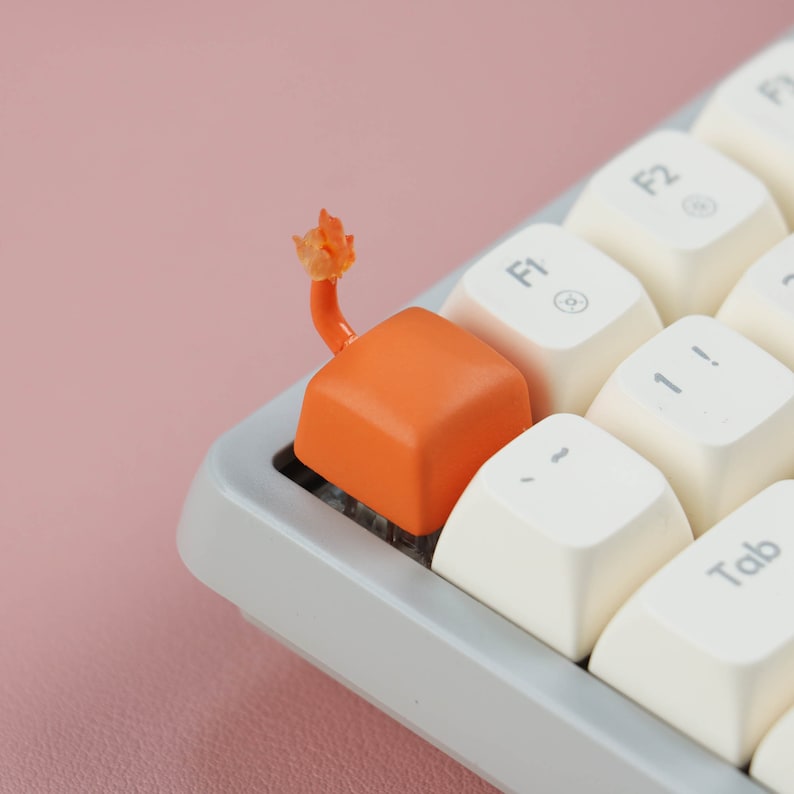 May include: A close-up of a white keyboard with orange keycaps. The keyboard has a white and gray design with a  "Tab" key and function keys labeled "F1" and "F2".