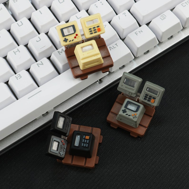 May include: Two sets of miniature retro-style electronics on wooden bases. Each set includes a calculator, a video game console, and a computer monitor. The sets are in black and brown, and gray and brown.