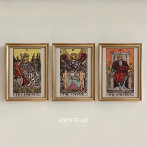 May include: Three framed tarot card prints. The prints feature the Empress, the Lovers, and the Emperor. Each card has a gold frame. The text "THE EMPRESS", "THE LOVERS", and "THE EMPEROR" are printed at the bottom of each card.