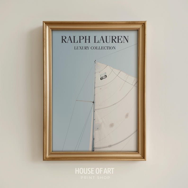 May include: A framed print featuring a sailboat with a white sail against a light blue sky. The print is in a gold-colored frame. The text "RALPH LAUREN LUXURY COLLECTION" is at the top. The text "HOUSE OF ART PRINT SHOP" is at the bottom.