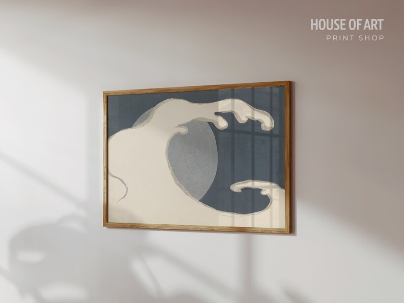 May include: A framed print of a stylized wave in shades of blue and white. The wave is depicted in a minimalist style, with a single, large crest and a smaller, trailing wave. The print is framed in a natural wood frame.