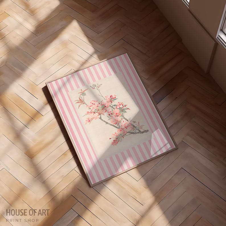 May include: A framed floral print featuring a branch with pink blossoms. The artwork is set against a cream background with a pink striped border. The print is displayed on a wooden floor, with the text "HOUSE OF ART PRINT SHOP" visible.