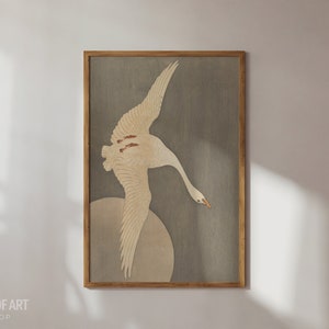 Op de afbeelding: Een ingelijste print van een witte vogel met bruine markeringen die vliegt tegen een grijze achtergrond. De vogel is in klassieke Japanse stijl.