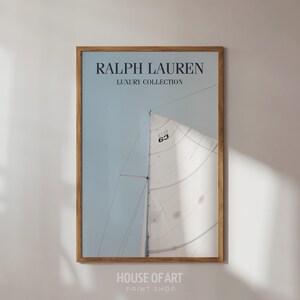 May include: A framed print featuring a sailboat with a white sail against a light blue sky. The print has the text "RALPH LAUREN LUXURY COLLECTION" at the top. The frame is made of wood.